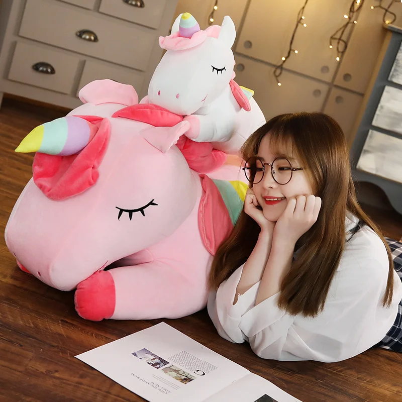 Enhörning gosedjur i kawaii-stil, stor hästkudde för barn och flickor, 25–100 cm 24 Person ligger bredvid en stor och en mindre rosa enhörning i plysch.