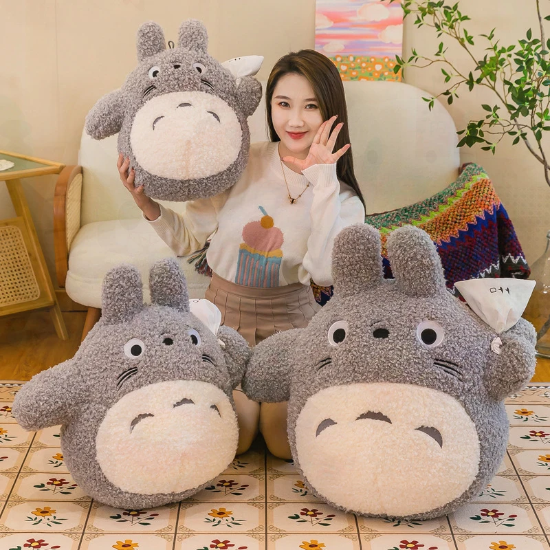 Totoro gosedjur i kawaii-stil som mjuk plyschkudde med vit papperspåse, 50–70 cm 18 Grå figurer i olika storlekar visas tillsammans med en person i ett rum.