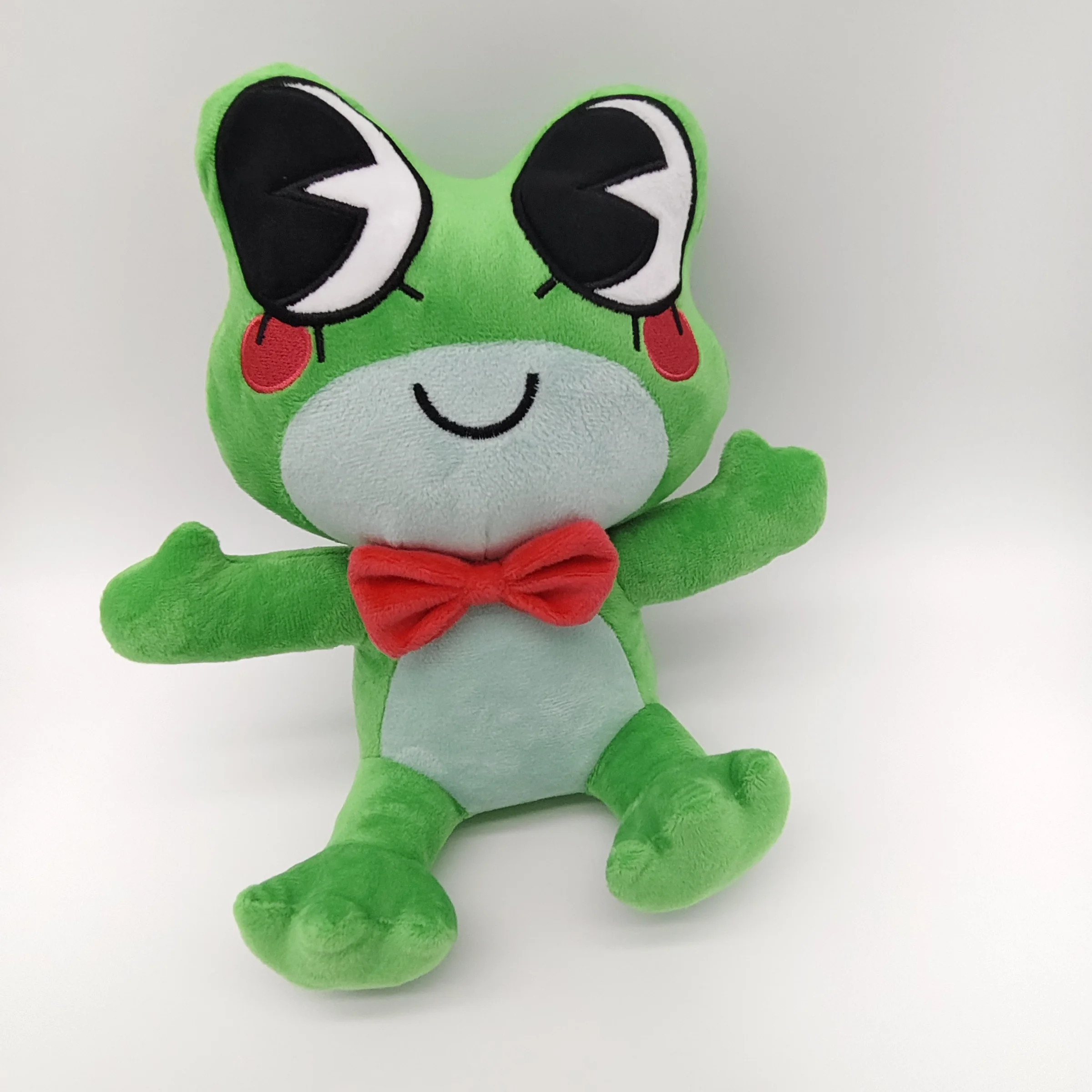 Groda gosedjur, söt och tecknad style, grön kawaii stil skrivbordsdekoration 21 Grön grodplysch med ljus mage, stora ögon och röd fluga, fotograferad framifrån.