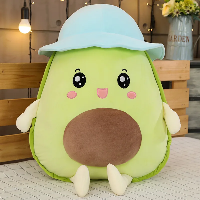 Avokadokudde som gosedjur i flera figurvarianter, med hatt i kawaii-stil, 30–80 cm 19 Framifrån syns avokadomjukisens ansikte, bruna mittparti och ljusblå hatt.
