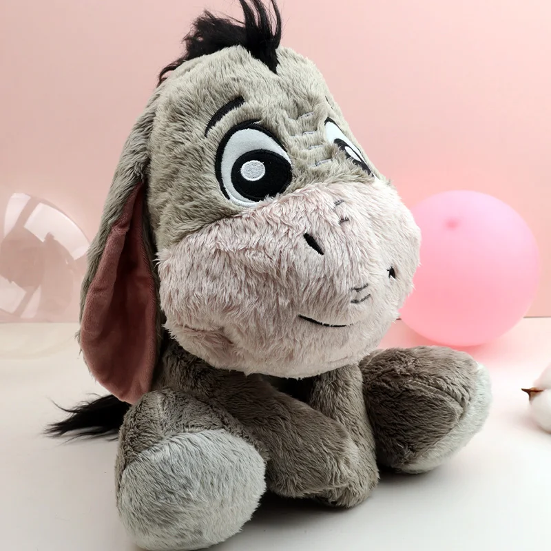 Eeyore gosedjur, fluffig figur i tecknad stil från My Friends Tigger and Pooh, 26 cm 20 Grå åsneplysch med rosa mule och långa öron, sittande mot ljusrosa bakgrund