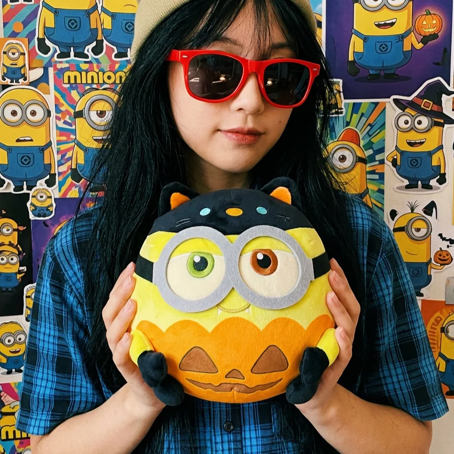 Vampyrklädd Minions-pumpabjörn i cosplaydesign, söt Halloweenprydnad för filmälskare 22 Person som håller ett Minions-gosedjur i pumpainspirerad stil.