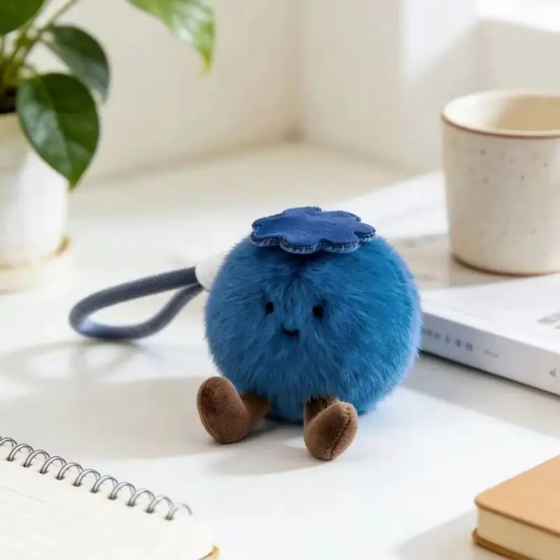 Nyckelring med blåbärsdesign, fluffig lyckobringare och flera figurvarianter 22 Blåbärsfiguren visas fristående på ett ljust skrivbord.