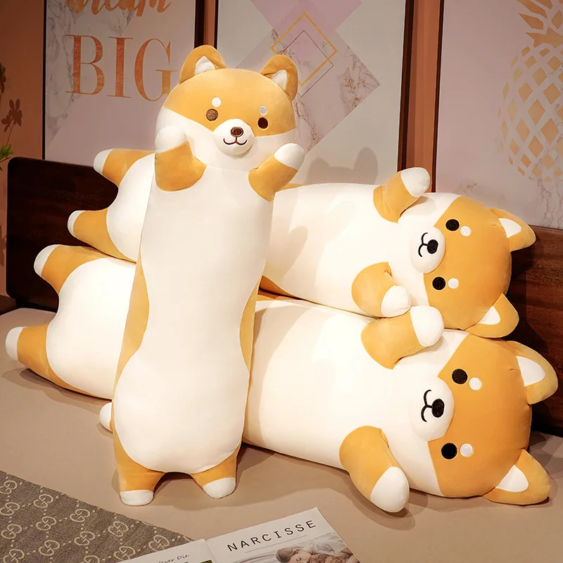 Katt gosedjur i form av lång Shiba Inu-hund, mjuk kudde med Corgi och Chai, 50–150 cm 40 Tre djurformade plyschfigurer, med fokus på en orangevit hundfigur som ligger på en säng.