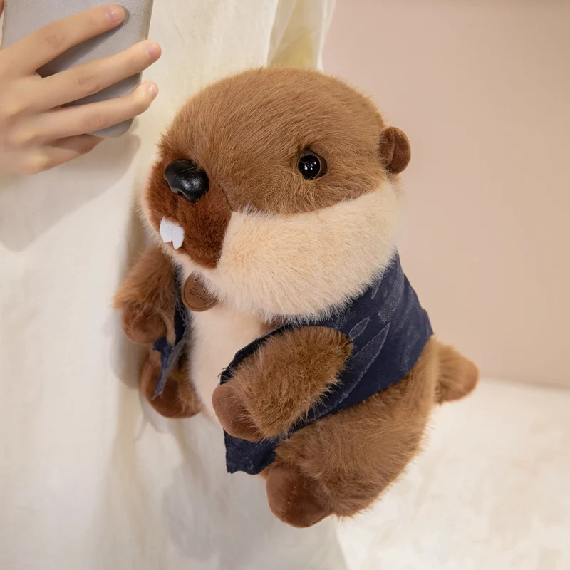 Sött marmot gosedjur med väst, naturtroget och fluffigt kramdjur med knubbig form 23–28 cm 22 Ett brunt djurformat plyschgosedjur hålls av en person.