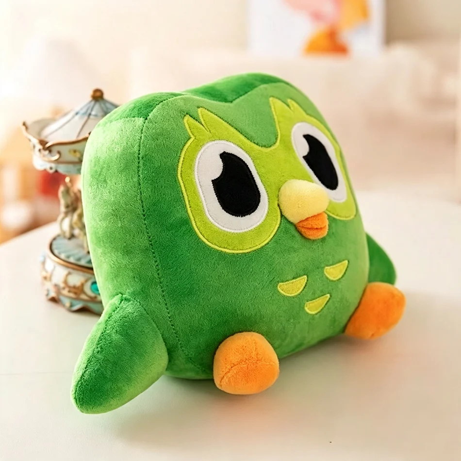 Grön uggla från Duolingo som mjukt gosedjur med karaktären Duo i söt tecknad stil 22 Duo-ugglan snett framifrån med stora ögon, gul-orange näbb och orange fötter.