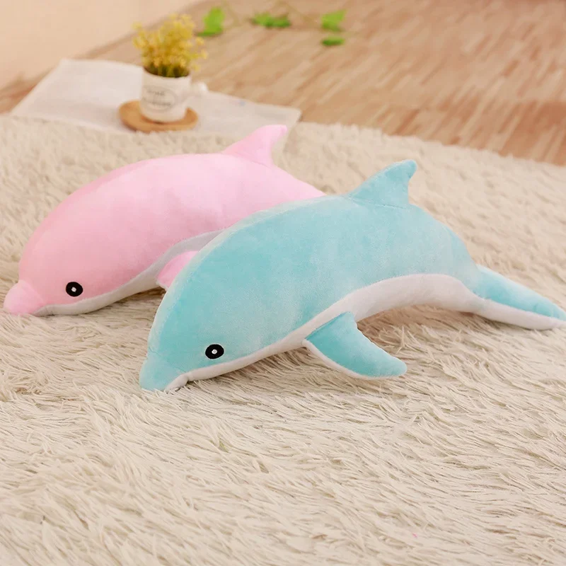 Delfin gosedjur som delfinkudde, 30 cm 29 Visa två delfinformade plyschfigurer i turkosblått och rosa med vita undersidor.