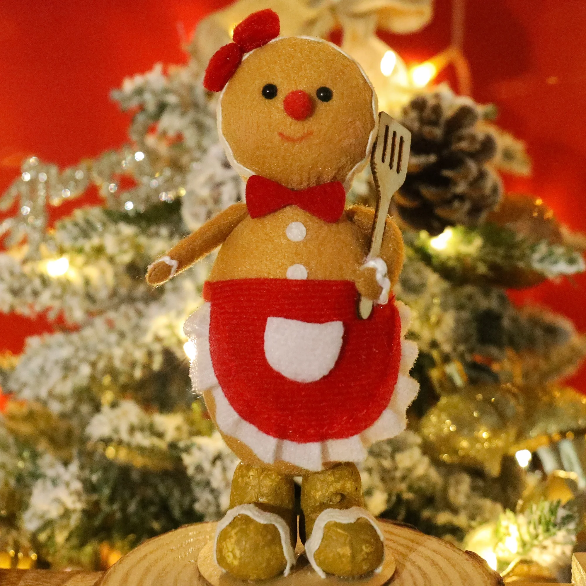 Gingerbread man som nyckelring, Sitter design och Chef design, mandekoration 24 Pepparkaksgubbe med röd rosett och förkläde står på en rund fot i julmiljö.