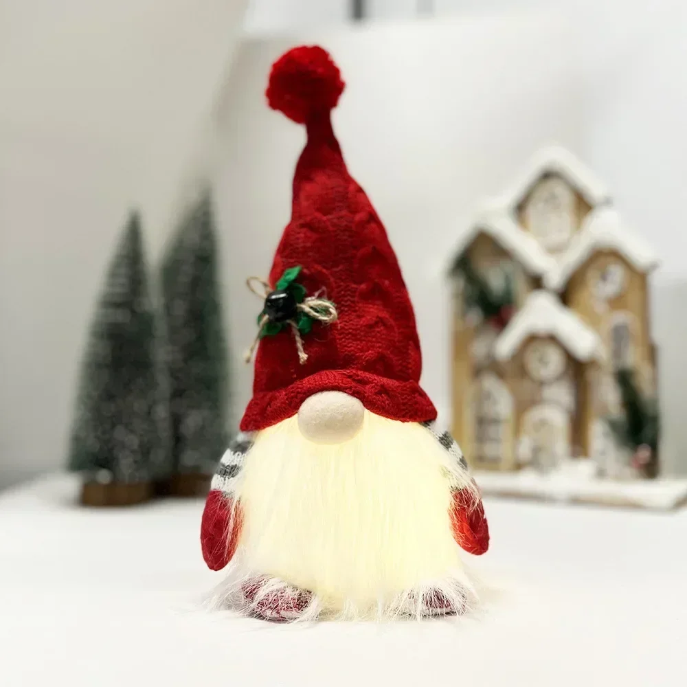 Julprydnader med flera figurvarianter, stickad tomteluva och lykta i tomtestil 23 Julnisse med hög röd mössa och fluffig ljus kropp framför juldekorationer.