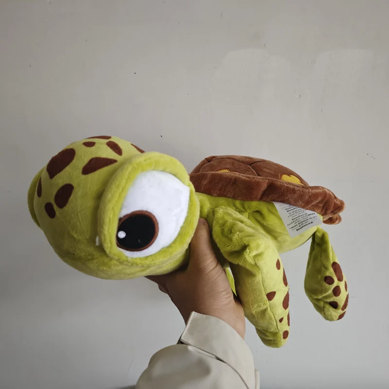 Sköldpadda gosedjur, lång och mjuk, med originaldesign från Finding Nemo, 40 cm 18 Visa sköldpaddans ansikte när den hålls upp, med den fästa etiketten synlig.