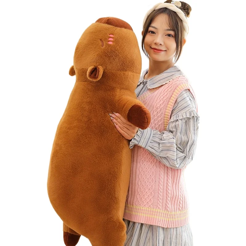 Kawaii kapybara gosedjur som mjuk, fluffig sovkudde för soffan, skolan och tupplur 20 En person som kramar en stor brun kapybaraformad plyschkudde.