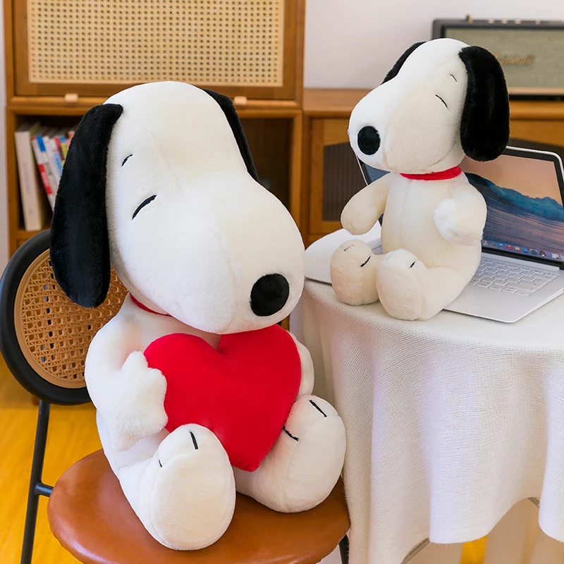 Snoopy som hundgosedjur, stor hjärtformad hundkudde i tecknad stil, 45–100 cm 22 Vit mjukishund med svarta öron håller ett rött hjärta i ett rum.