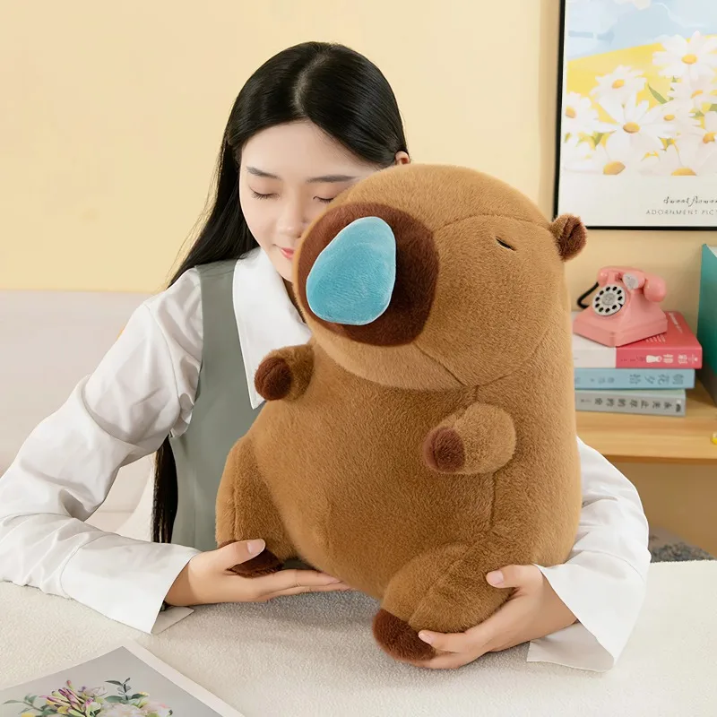 Kapybara gosedjur som stor kramkudde i tecknad kawaii-stil med snordetalj, 50 cm 22 En person kramar en rund brun plyschfigur.