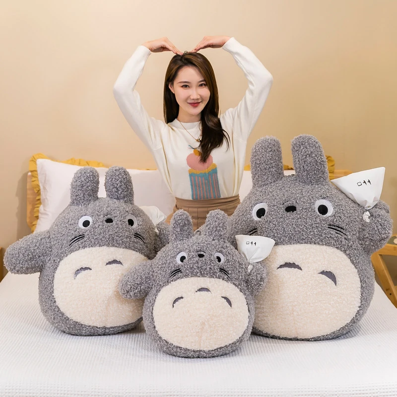 Totoro gosedjur som plyschkudde och kramkudde i tecknad anime-stil, 50–70 cm 21 Visa tre plyschfigurer i olika storlekar framför en person.