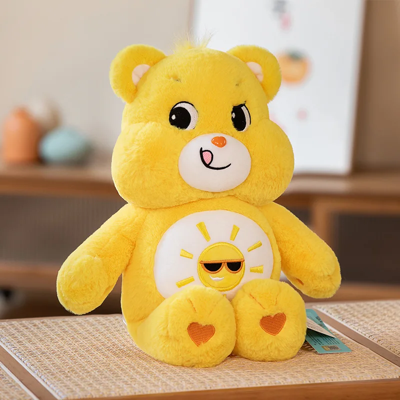 Sött Care Bears björn gosedjur med regnbågsdesign, mjuk kudde och charmig tecknad stil 25 Gul mjukisbjörn med solmotiv på magen, visad i helfigur.