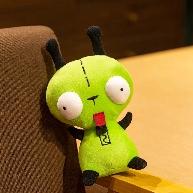 Hund gosedjur, Green och Alien invader, grön kawaii inspirerad alienfigur 20 Grön alienliknande plushfigur sedd snett framifrån nära en stol.