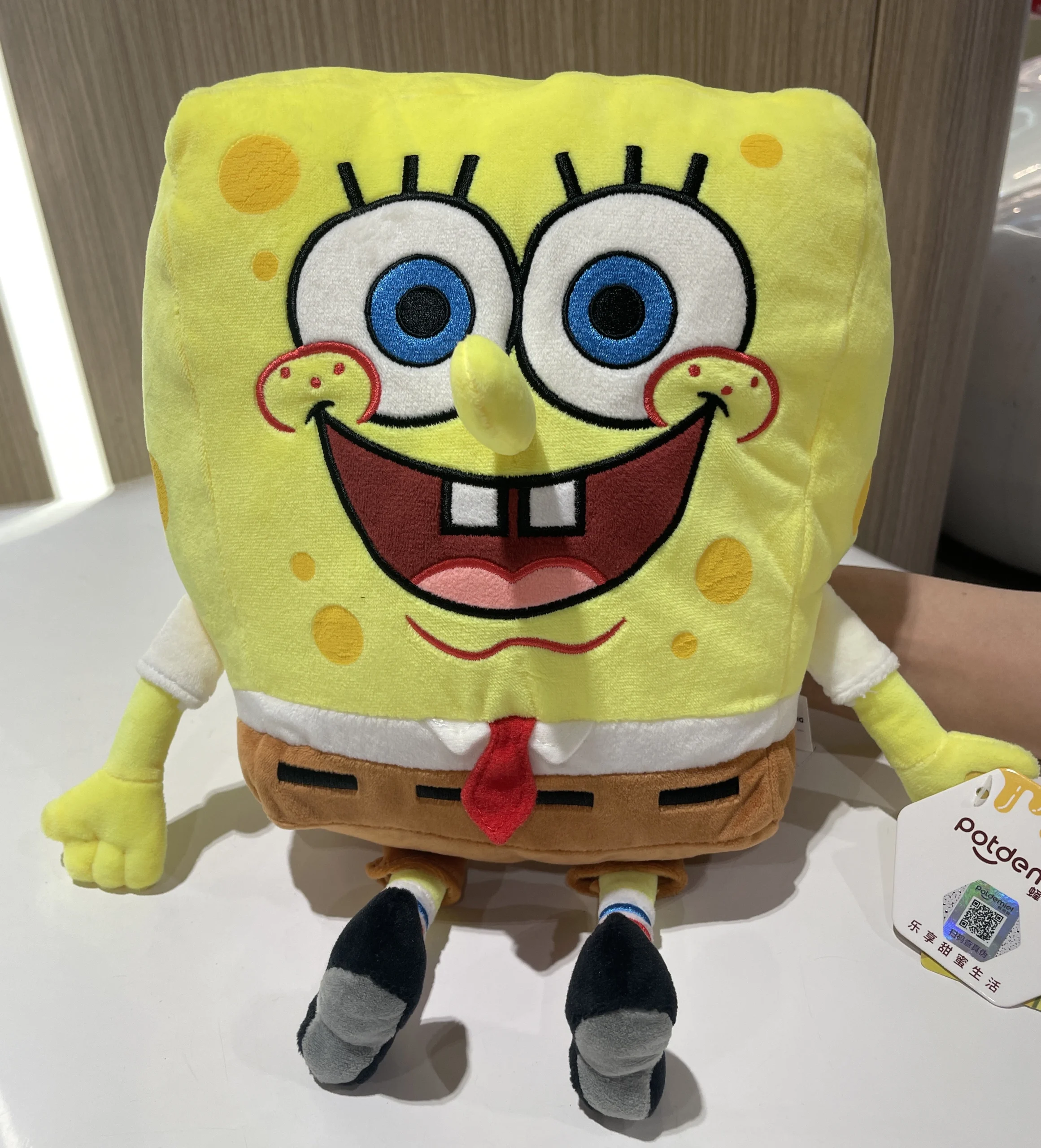 SpongeBob-karaktärer gosedjur som Halloweeninspirerad plyschkudde och prydnadskudde 24 Gult gosedjur med stora blå ögon och leende visas framifrån med skjorta, bruna shorts och svarta skor.
