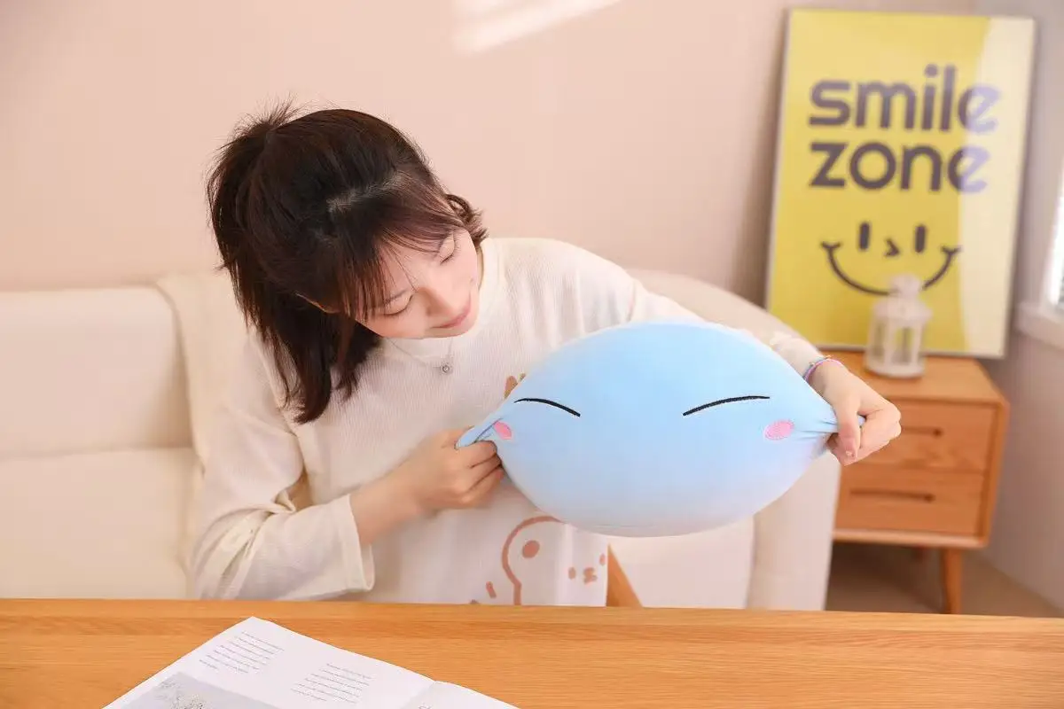 Tuanzi gosedjur i slimeform som plyschkudde med kawaii- och animeinspirerad design 20 En kvinna håller fram en ljusblå slime-mjukis och tittar på den.