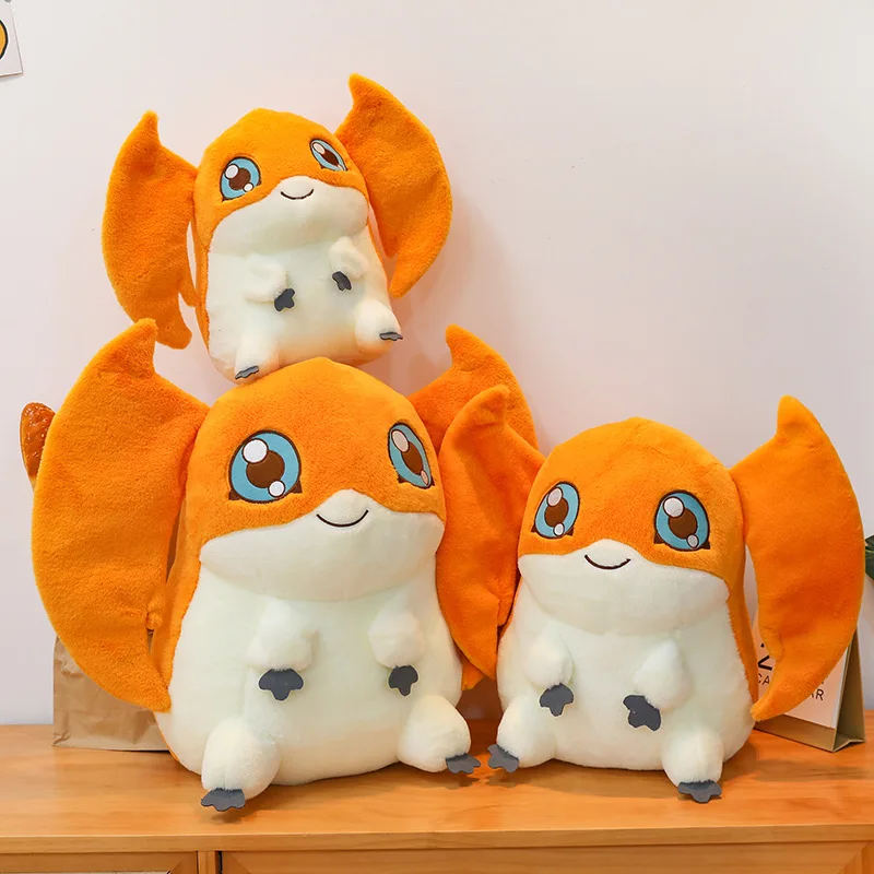 Patamon gosedjur som plyschkudde i söt animestil från Digital Monster, 35 cm 18 Tre matchande orange fantasifigurer med krämfärgade kroppar står tillsammans på ett bord.