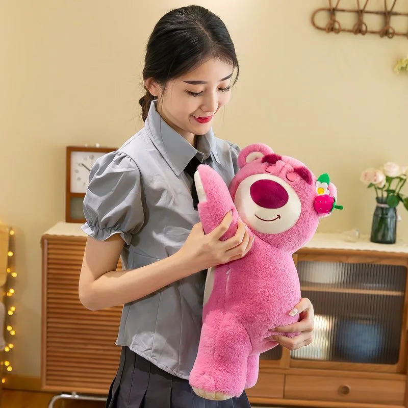 Disney Lotso björn gosedjur som jordgubbsinspirerad plyschkudde i tecknad stil 21 Visa en person som håller den rosa björnplushen upprätt.
