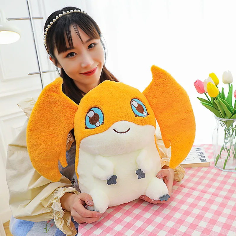 Patamon gosedjur som plyschkudde i söt animestil från Digital Monster, 35 cm 20 En person håller upp den orangea mjukisfiguren i ett ljust rum.