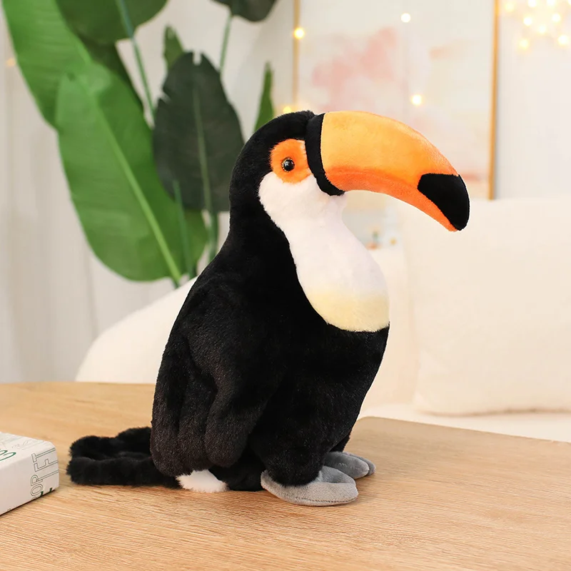 Gosedjur med flera figurvarianter i gullig, verklighetstrogen fågelform, 30 cm 23 Svartvit tukanplyschfågel med stor orange näbb visas stående från sidan.