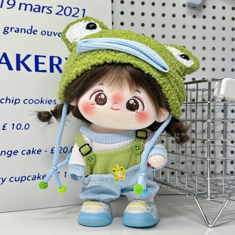 Groda gosedjur i sött klädset med tröja, ombyteskläder för dockor på, 20 cm 22 Plushdocka i grön outfit med ljusblå detaljer framför en butiksmiljö.